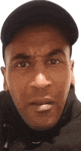 a close up of a man 's face wearing a black hat