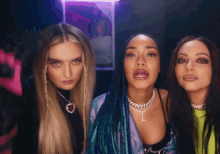 three women standing next to each other with one wearing a necklace with the letter l