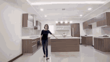 a woman walking in a kitchen with a large island