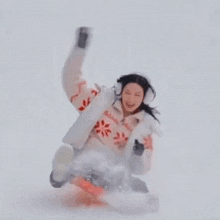 a woman wearing headphones is sliding down a snow covered hill .