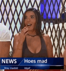 a woman in a black tank top is standing in front of a news report that says hoes mad .