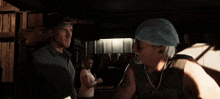 a man wearing a hat talks to another man in a room
