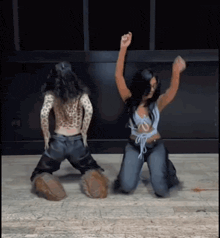two women are kneeling on the floor and dancing together .