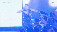 a wrestler is dancing in front of a crowd of people at a live event .