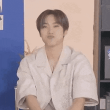 a young man in a white shirt is making a funny face while sitting in a chair .