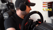 a man wearing headphones sits in front of a steering wheel with 1,542 on the screen