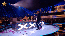 a man is dancing on a stage in front of a table that says xxx