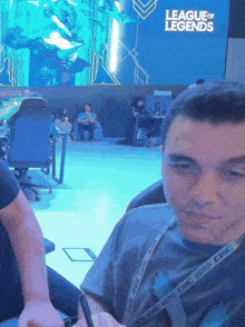 a man sitting in front of a screen that says league of legends on it