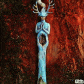 a statue of a woman with antlers on her head is on a tree trunk with pixiz written on the bottom