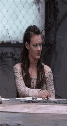 a woman with makeup on her face is sitting at a table with a map on it .