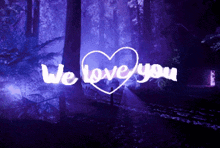 a sign that says we love you in a dark forest