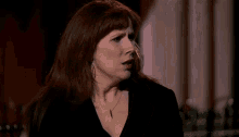 a woman with red hair is wearing a black jacket