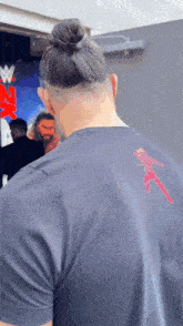 a man with a bun is wearing a black t-shirt with a picture of a woman on the back