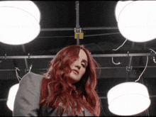 a woman with red hair is standing in front of a bunch of white lights