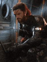 a man with a beard and a snake eye is sitting down