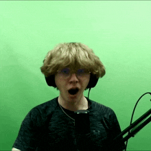 a man wearing headphones and a under armour shirt stands in front of a microphone