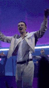 a man in a white jacket is singing into a microphone on a stage