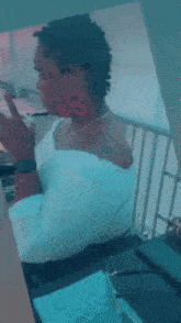 a woman is sitting at a table drinking from a straw and looking at the camera .