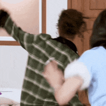 a man in a green plaid shirt is standing next to a woman in a blue shirt and they are dancing .