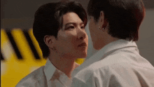 a couple of men are standing next to each other and touching each other 's faces .