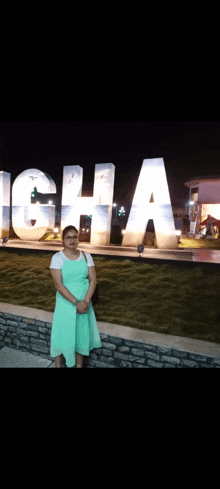 a woman in a green dress is standing in front of a large sign that says ghana
