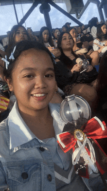 a girl in a denim jacket is holding a light stick with a red bow on it