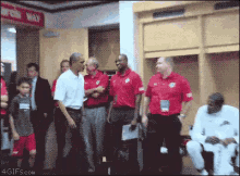 a group of men in red shirts are standing in a locker room with a sign that says work way