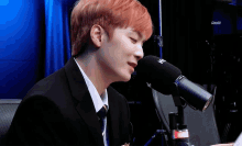 a man in a suit and tie is speaking into a microphone with the letter w on it