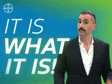 a man in a suit is standing in front of a sign that says it is what it is