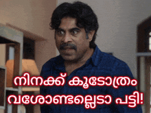 a man with a mustache stands in front of a sign that says ' malayalam '