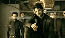 a man in a suit and tie is standing in front of a group of men .