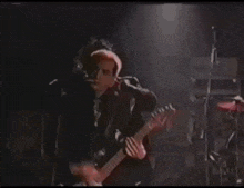 a man is playing a guitar on a stage in the dark .