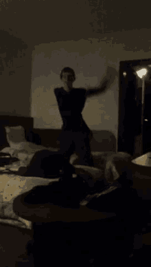 a man in a black shirt is jumping in the air in a dark room