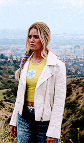 a woman wearing a yellow crop top and a white jacket