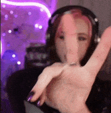 a woman wearing headphones is making a peace sign with her finger .