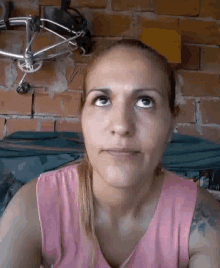 a woman in a pink tank top is looking up at the camera .