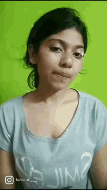 a woman wearing a blue shirt with the word jim on it is making a funny face
