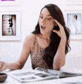 a woman sitting at a table with a magazine on the wall that says ego on it