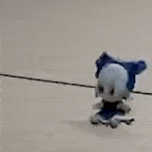 a blue and white stuffed animal is standing on a tile floor .