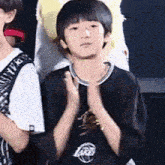 a young boy wearing a lakers shirt is clapping his hands .