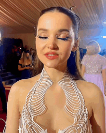 a close up of a woman 's face with a white necklace around her neck