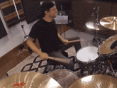 a man playing drums with a paiste cymbal in the background