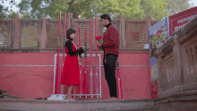 a man is giving a rose to a little girl in front of a red wall that says padma vihar