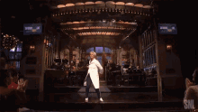 a woman is dancing on a stage in front of a snl screen