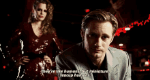 a man in a suit is talking to a woman in a red dress while a woman stands behind him .