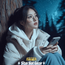 a woman wearing glasses is leaning against a tree and looking at her phone