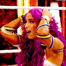 a woman with purple hair is standing in a ring with her hands on her head