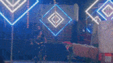 a man and a woman are riding a bike in front of a neon sign