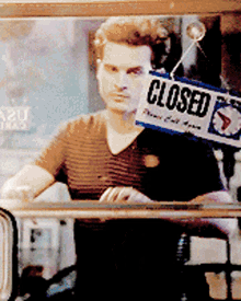 a man is looking out a window with a sign that says closed