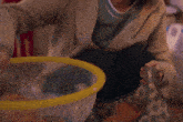 a woman is sitting on the floor with a yellow bucket in her hand